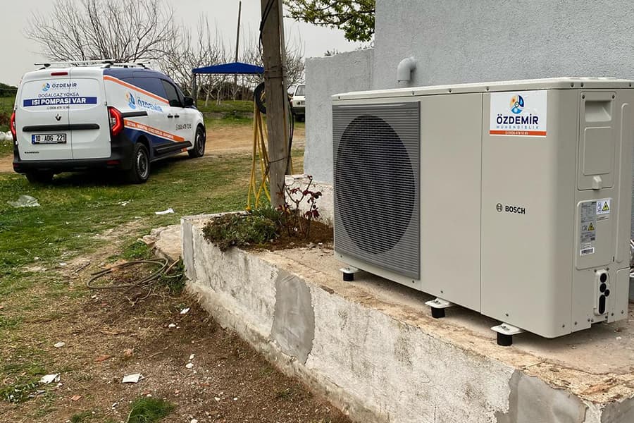 Bahçe duvarı üzerine kurulmuş Bosch ısı pompası dış ünitesi; arkada Özdemir Mühendislik servis aracı